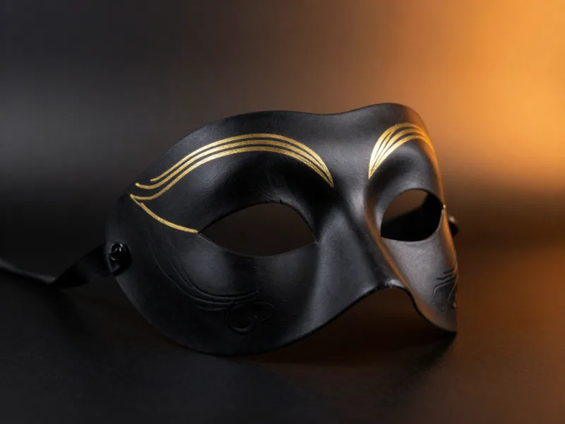Verzierte Maske in mattem Schwarz mit feinen Goldlinien über den Brauen